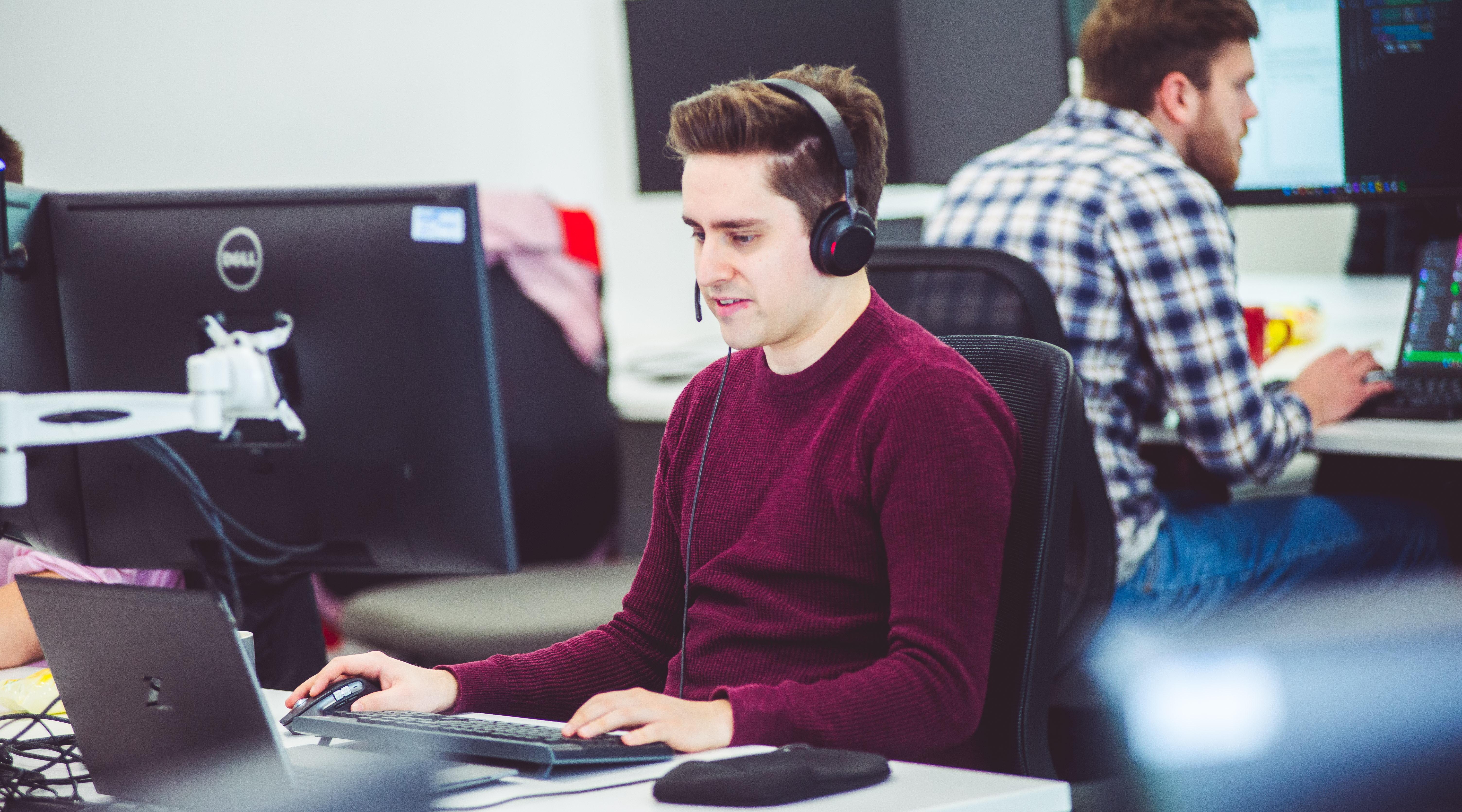 A male sitting at a computer wearing a headset with a microphone